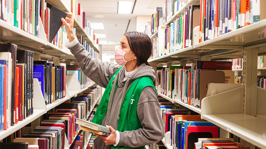 person reaching to books on a shelf